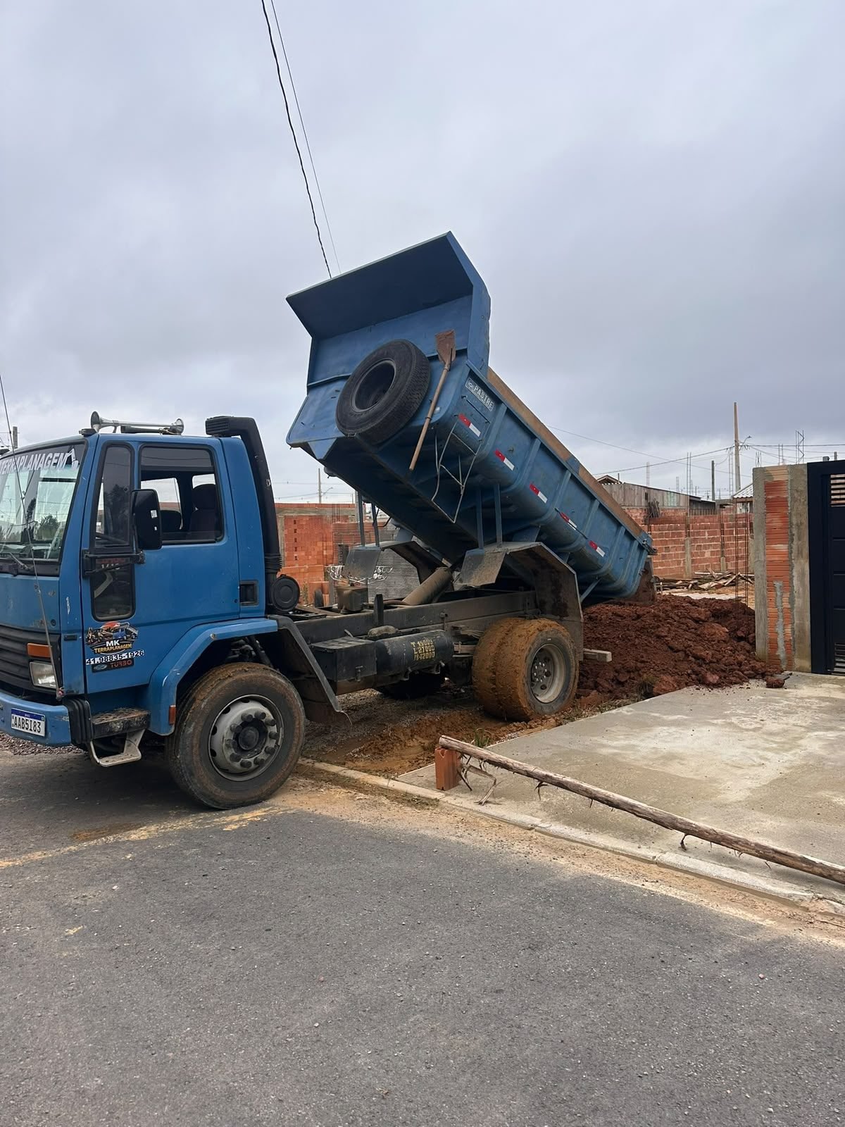 Caminhão basculante da MK Terraplanagem despejando terra em obra